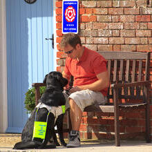 A man sat on a bench with his assistance dog