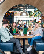 Two women and a man sit in a booth at a restaurant