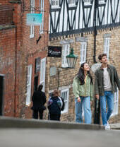 A woman and a man walk up a steep hill in a heritage City