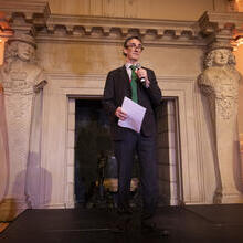A man on a stage welcoming delegates at a trade event