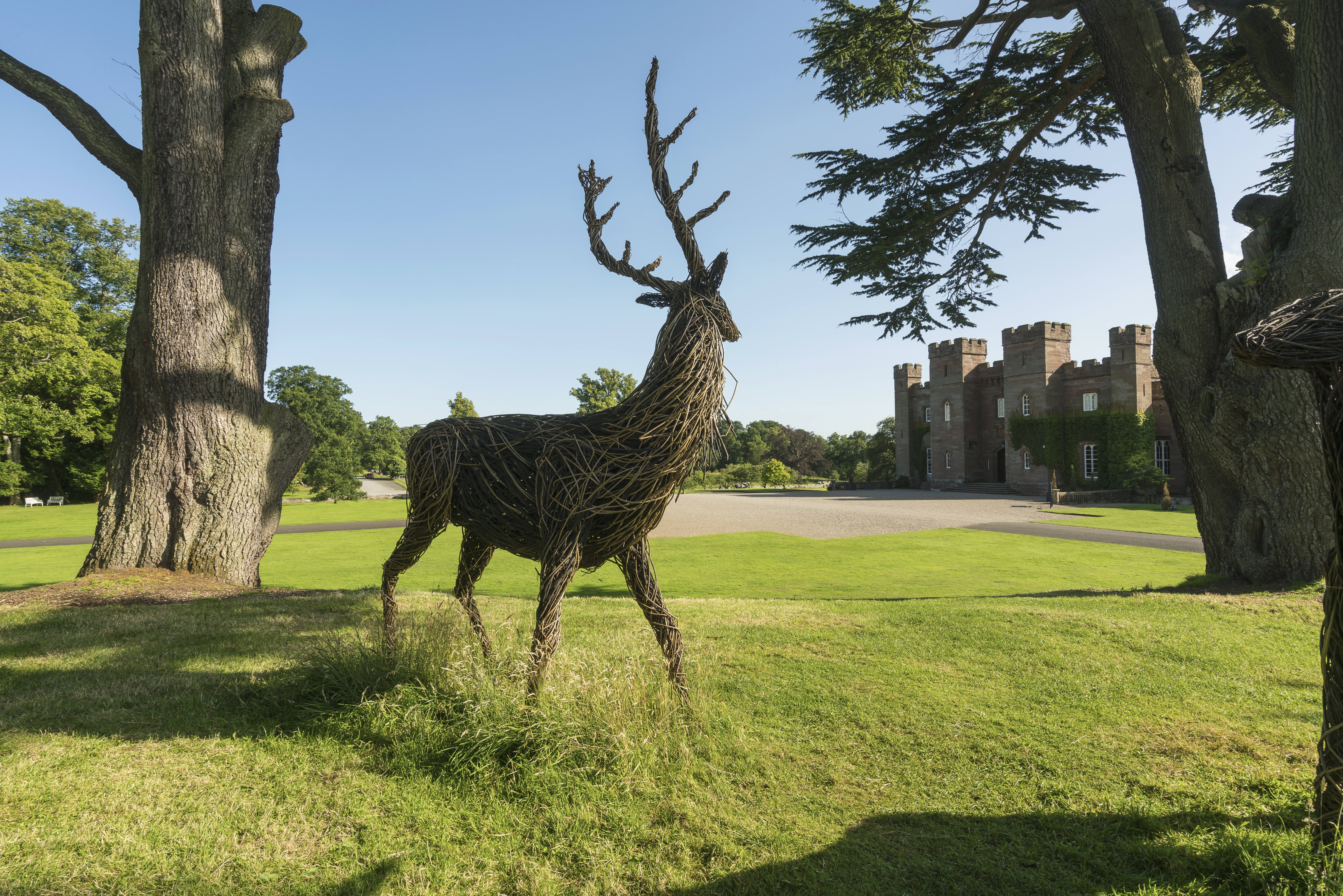 A wooden sculpture of a deer outside a castle.