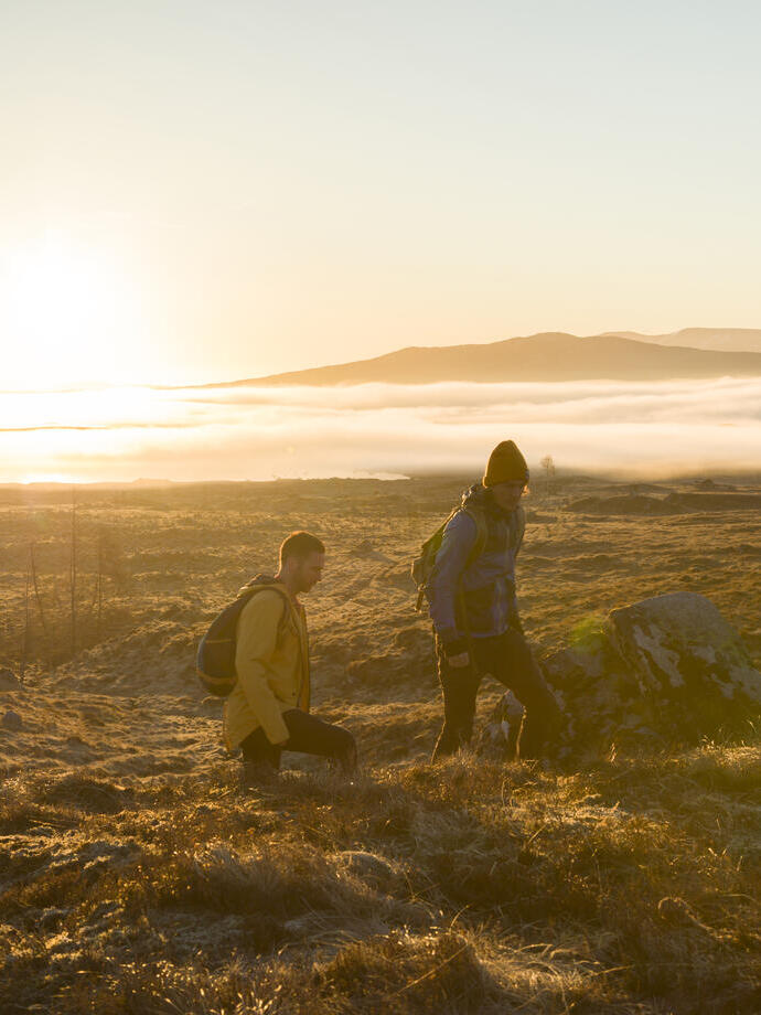 Deux hommes faisant une randonnée dans les hautes terres au coucher du soleil. Rayons de soleil