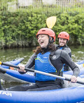 People smiling and laughing while kayaking down a river in Chester