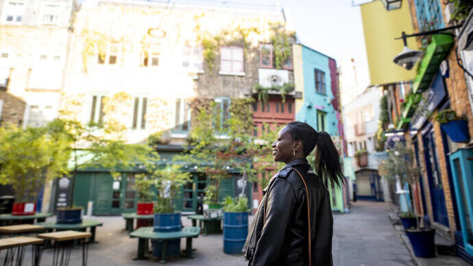 Female tourist exploring a London shopping courtyard with shops and outdoor seating.