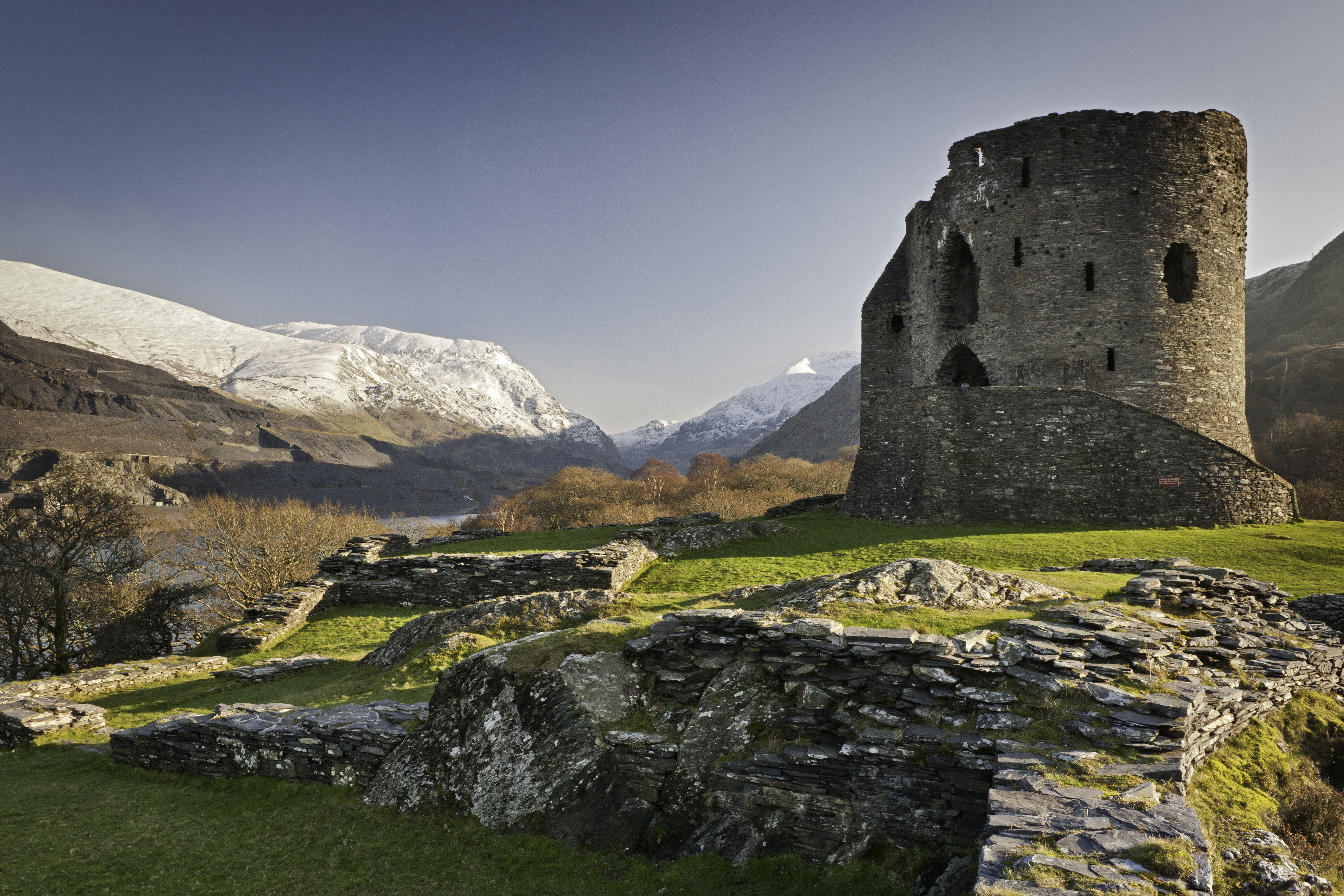 Ruins of a castle in the countryside surrounded by mountains.