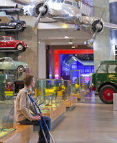 Man sitting down, looking at the displays in a museum holding his crutches