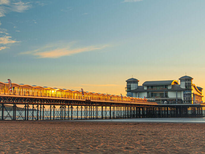 A majestic pier stretching out into the ocean with the tide out at sunset.