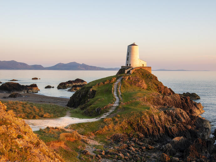 A path leading to a lighthouse on a prominent rocky outcrop by the sea