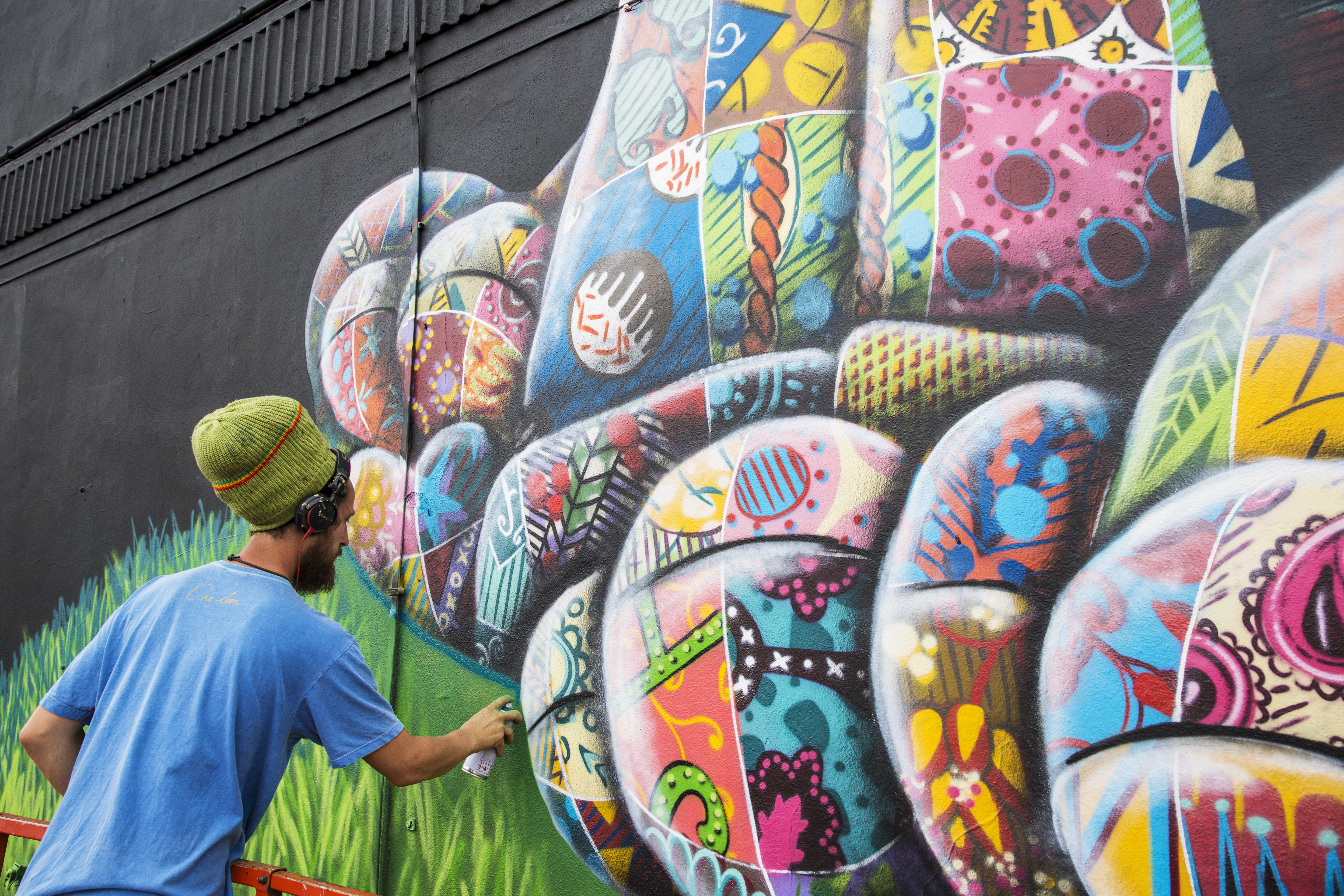 An artist using spray paint to design a piece of street artwork.