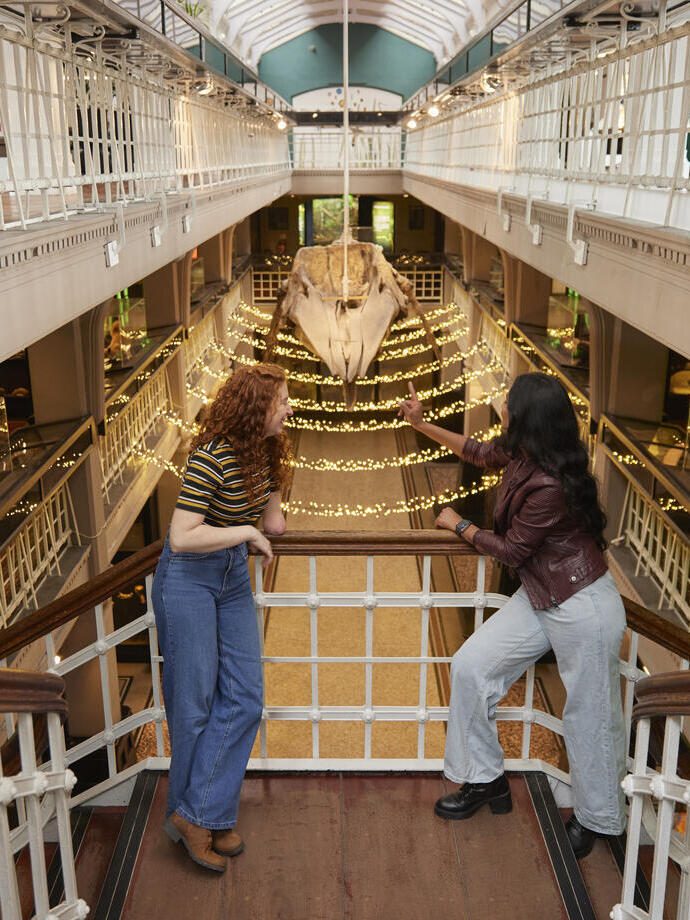 Deux femmes discutent et rient en visitant l'exposition préhistorique dans un grand musée.