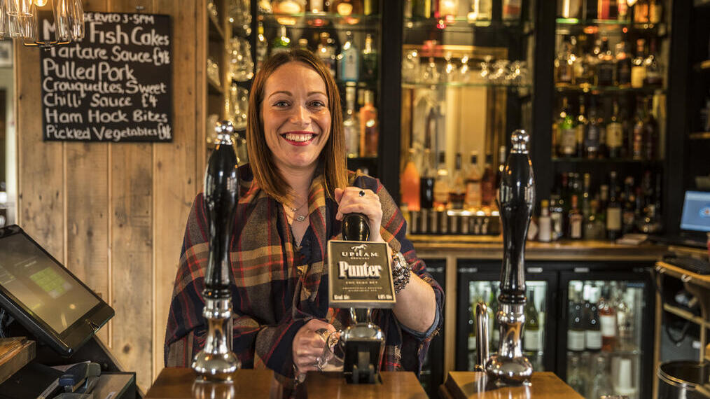 Une femme servant des boissons derrière le bar d'un pub