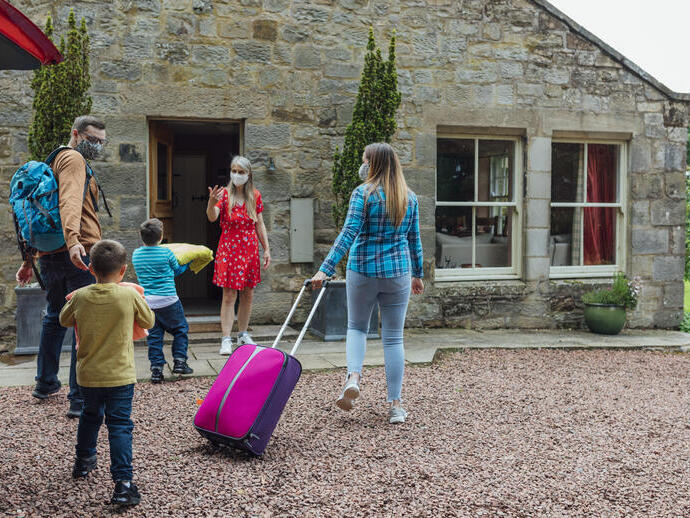 Family arriving at a Bed and Breakfast home, met by the owner