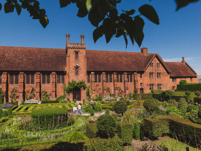Two women walk through the gardens of a heritage house