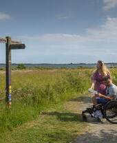 A man who uses a wheelchair and a woman review a map in the countryside