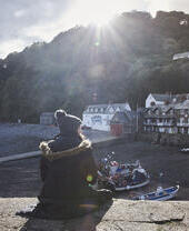 Woman sitting on harbour wall in the sunshine