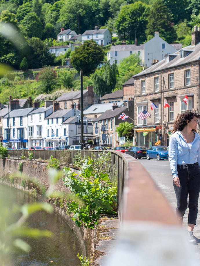 Two women walk down a main street in a hillside town