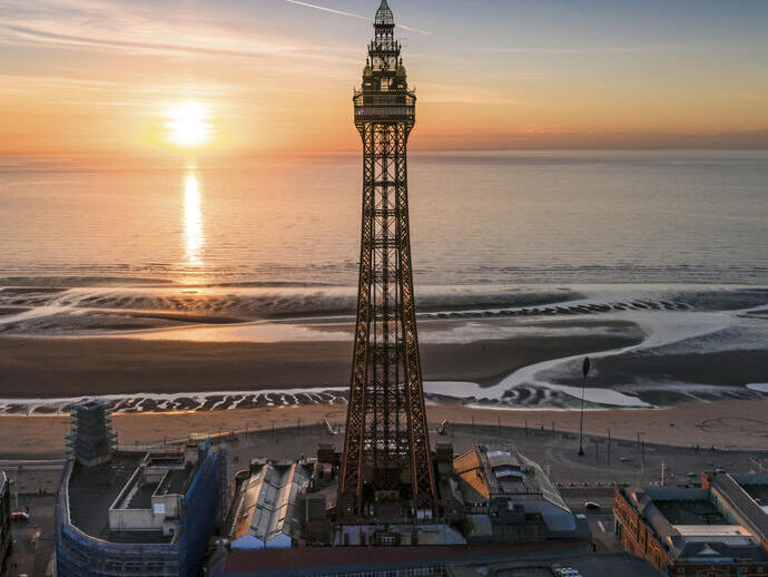 Tall tower on the side of the beach with the sun setting over the sea