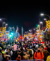 Nigh scene of crowd at festival, with luminaries hanging over the street