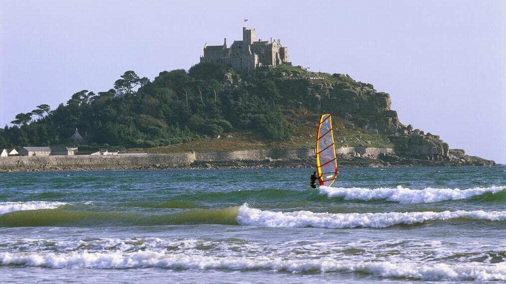 Une personne faisant de la planche à voile au large du château de St Michael's Mount, en Cornouailles