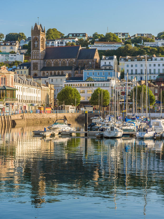 An English harbour with boats moored and village in the background