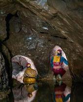 A part-flooded natural cave chamber with two lead miners' tunnels blasted at the far end in Speedwell Cavern in Castleton, Derbyshire.