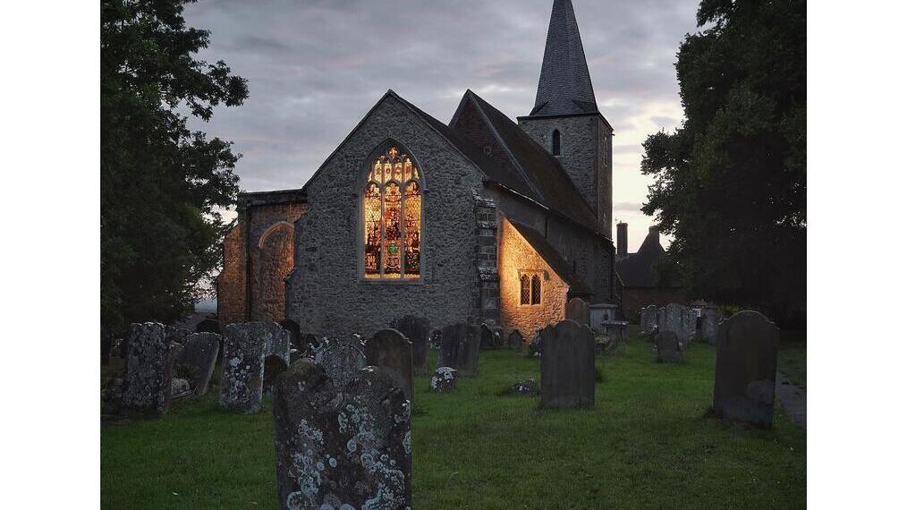 A church lit up at dusk in Pluckley, Kent