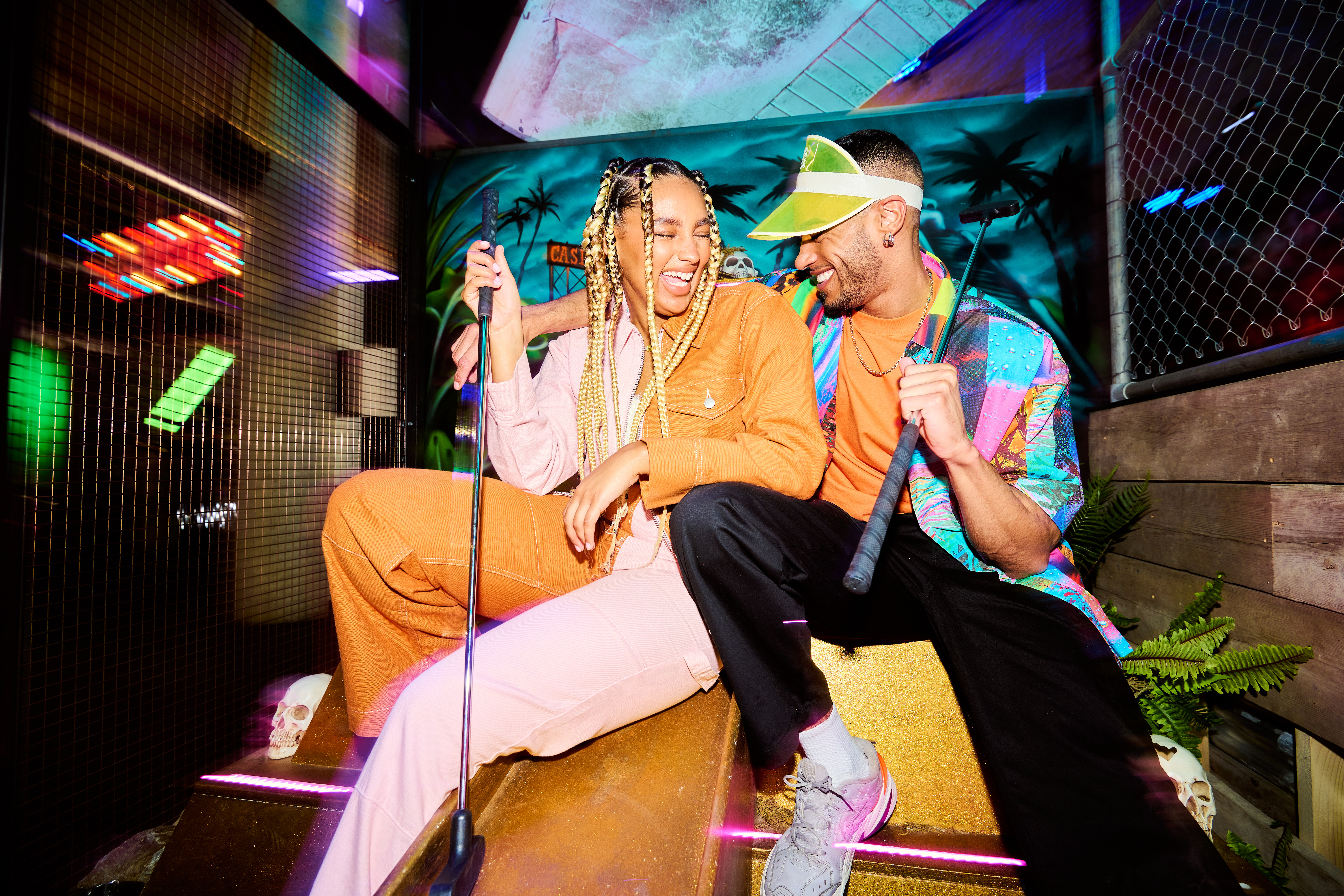 Two people posing with golf clubs at Junkyard Golf in Oxford