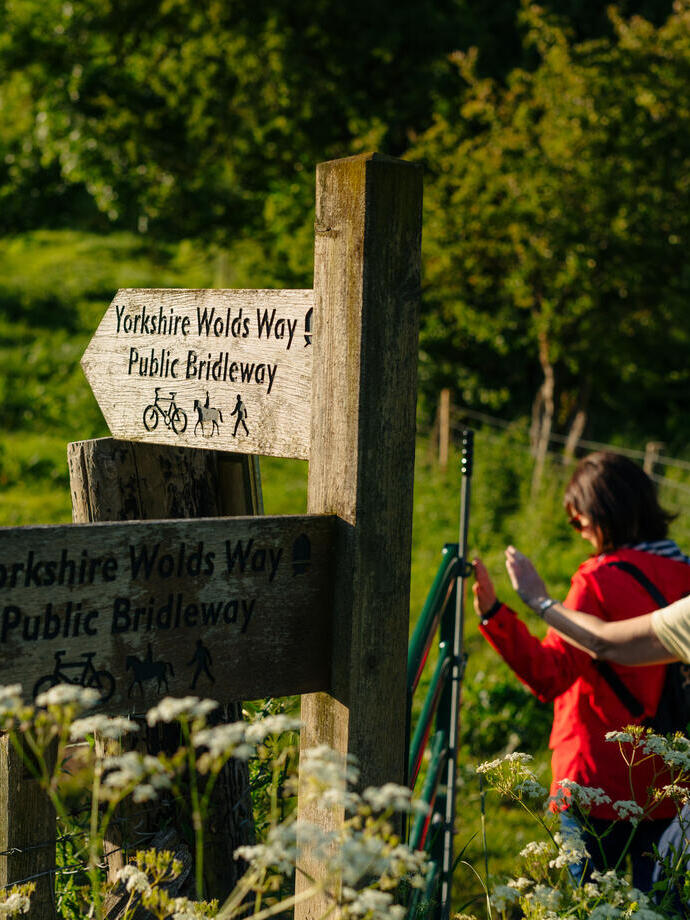 Two women walking in countryside passing sign posts