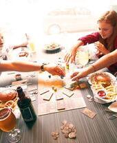 A family playing a board game while eating food at a cafe while playing board games