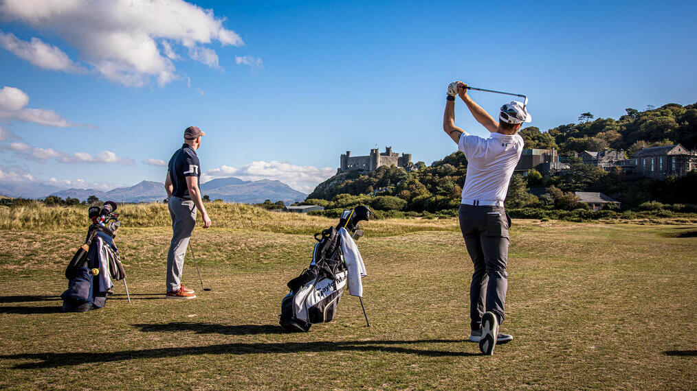 A pair of golfers teeing off at Royal St David's Golf Club in Wales