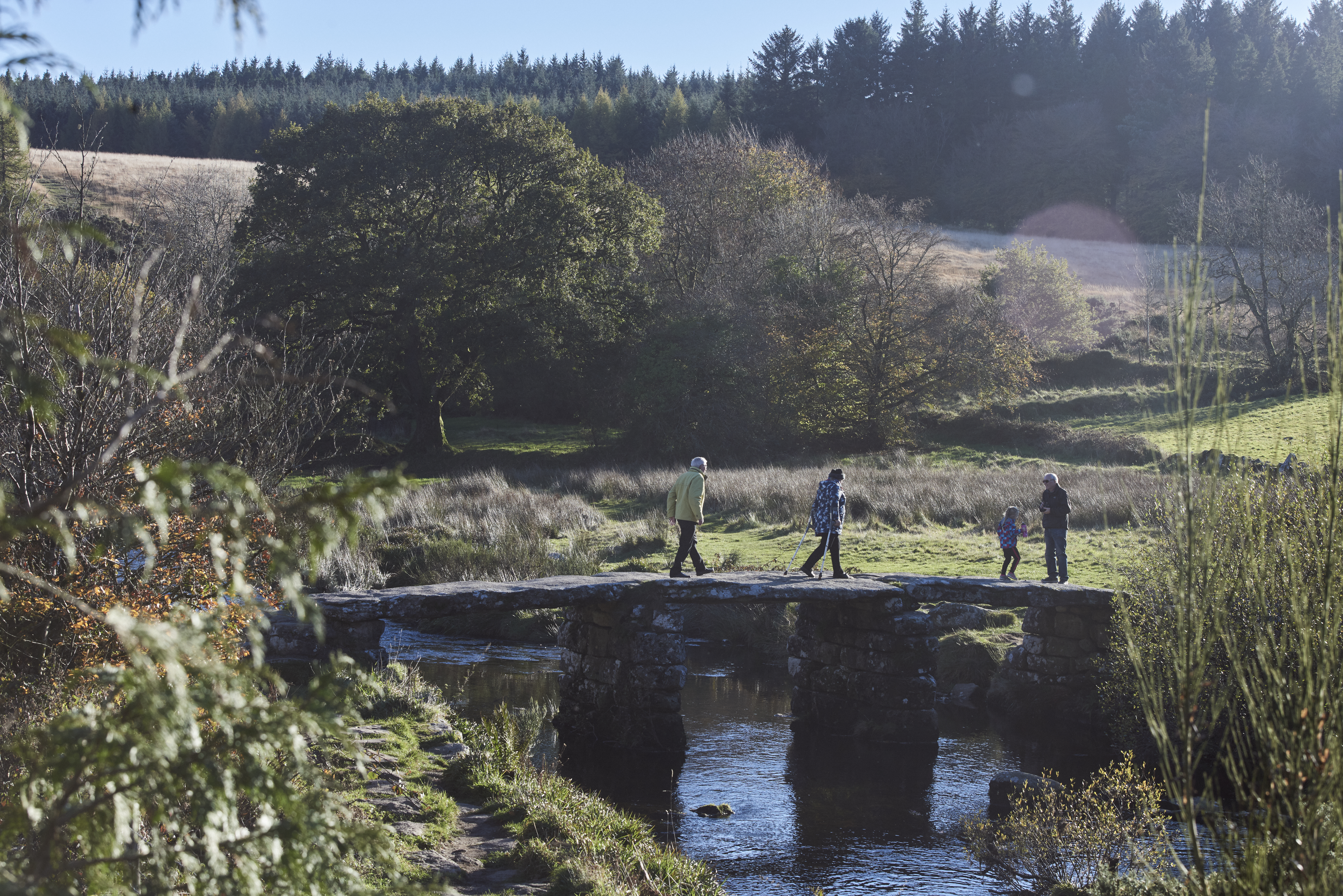 People walking on stone bridge across river