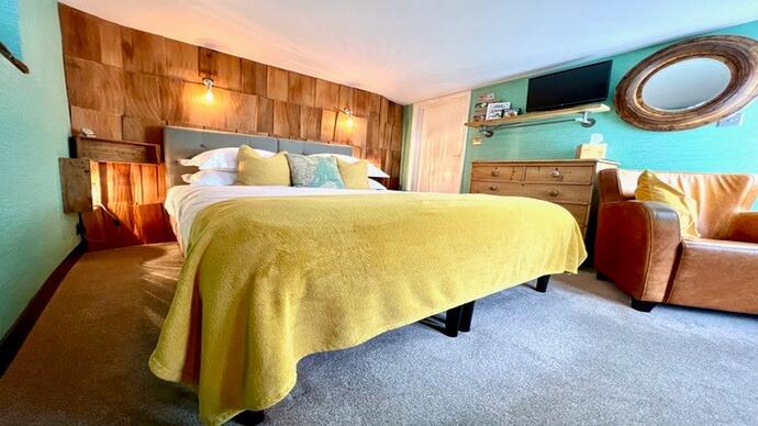 A bedroom with yellow bedspread and a wooden feature wall.