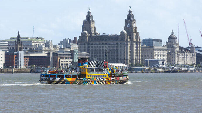 A view to a ferry on a river in front of the Liver building