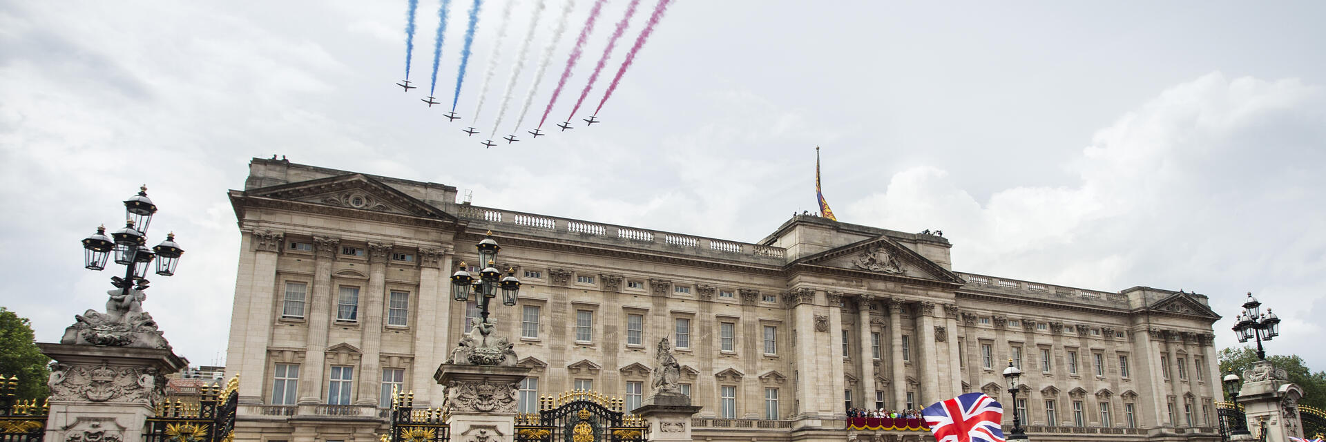 Getti con scie di fumo colorato volano in formazione sopra la folla e un palazzo