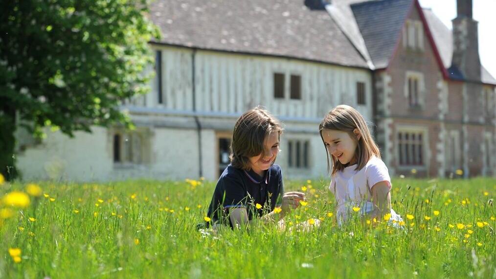 Zwei Kinder sitzen auf einem Feld und pflücken Blumen