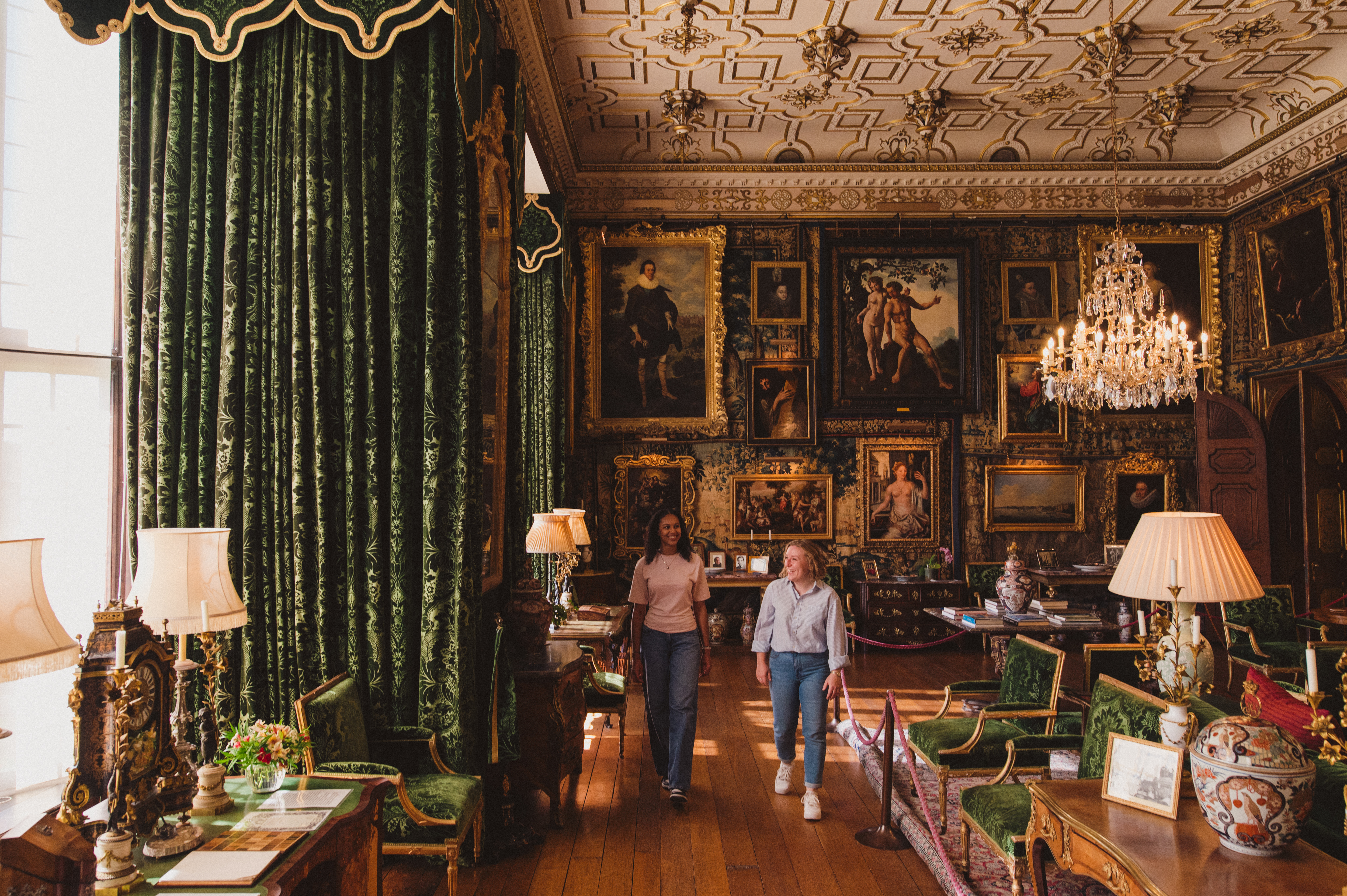 Two women walk through an ornate room in a heritage house