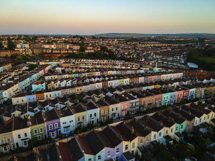 Fila de casas coloridas una al lado de la otra en una zona residencial, vista aérea al atardecer.
