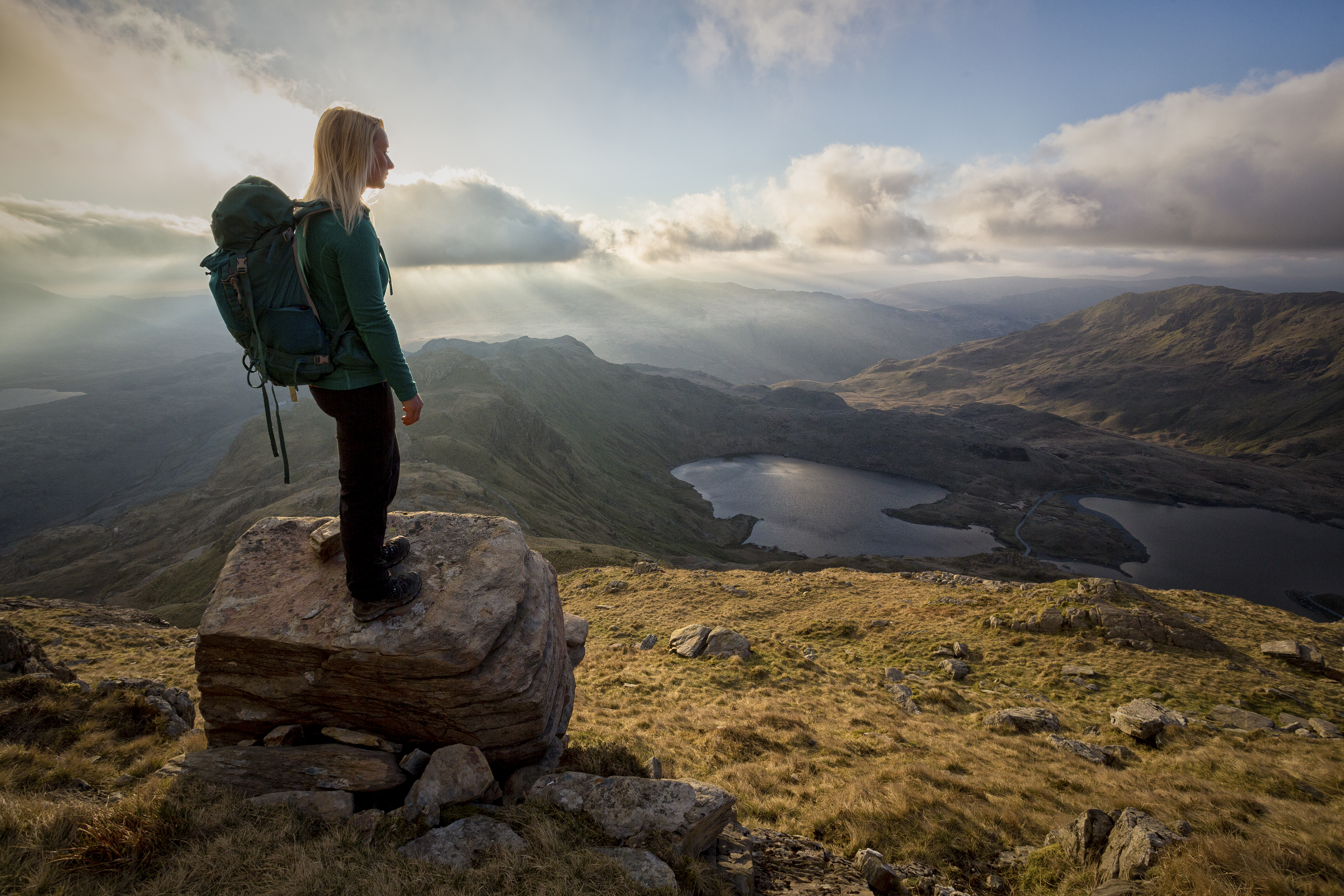 A young woman standing on rocks at a lookout point.