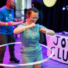 A lady dancing with a hula hoop at a centre for the arts.