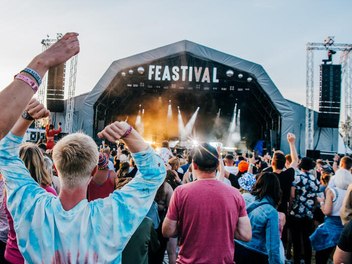 Large crowd dancing in front of a stage in the day at the Big Feastival in The Cotswolds.