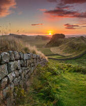 View along long stone wall over the fields at sunset