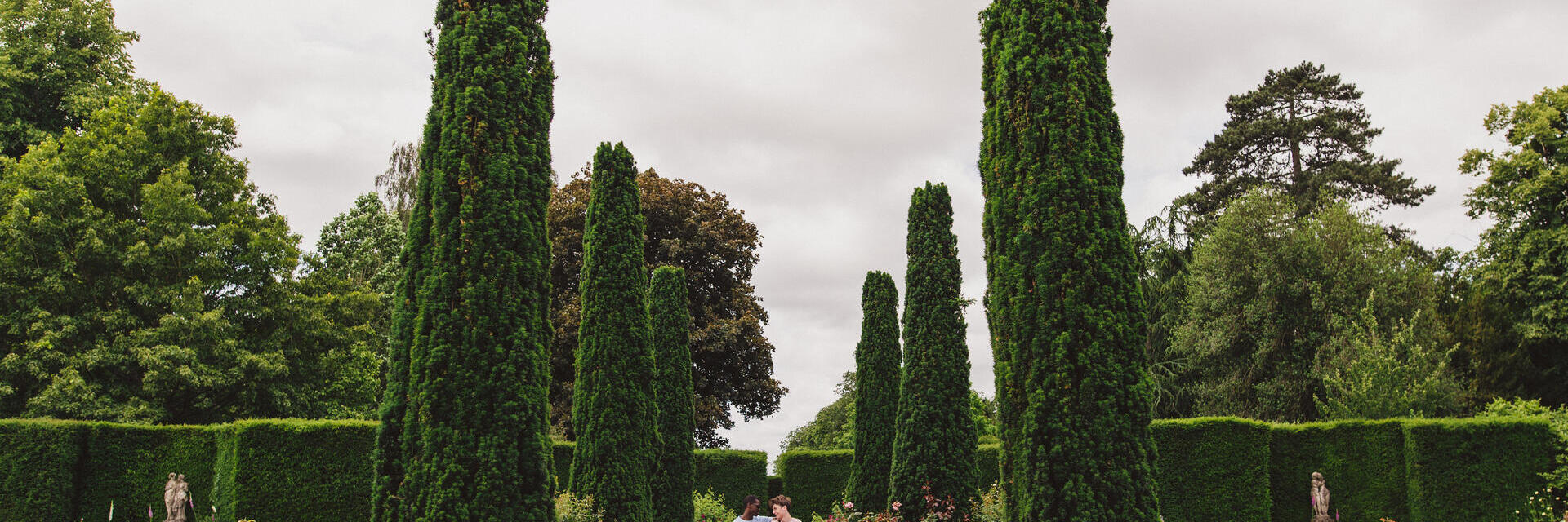 Dos jóvenes pasean por unos jardines ornamentados