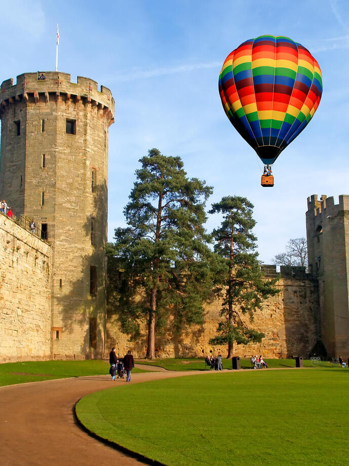 Un globo aerostático flota sobre un castillo y sus cuidados jardines.