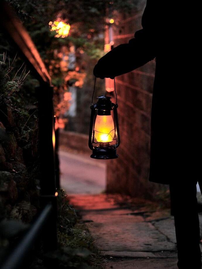 A man standing with a lantern in a dark street on a ghost walk through the town of Whitby, North Yorkshire