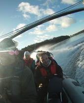 A group of people passing under an iron bridge on a speedboat in Snowdonia/Eryri National Park