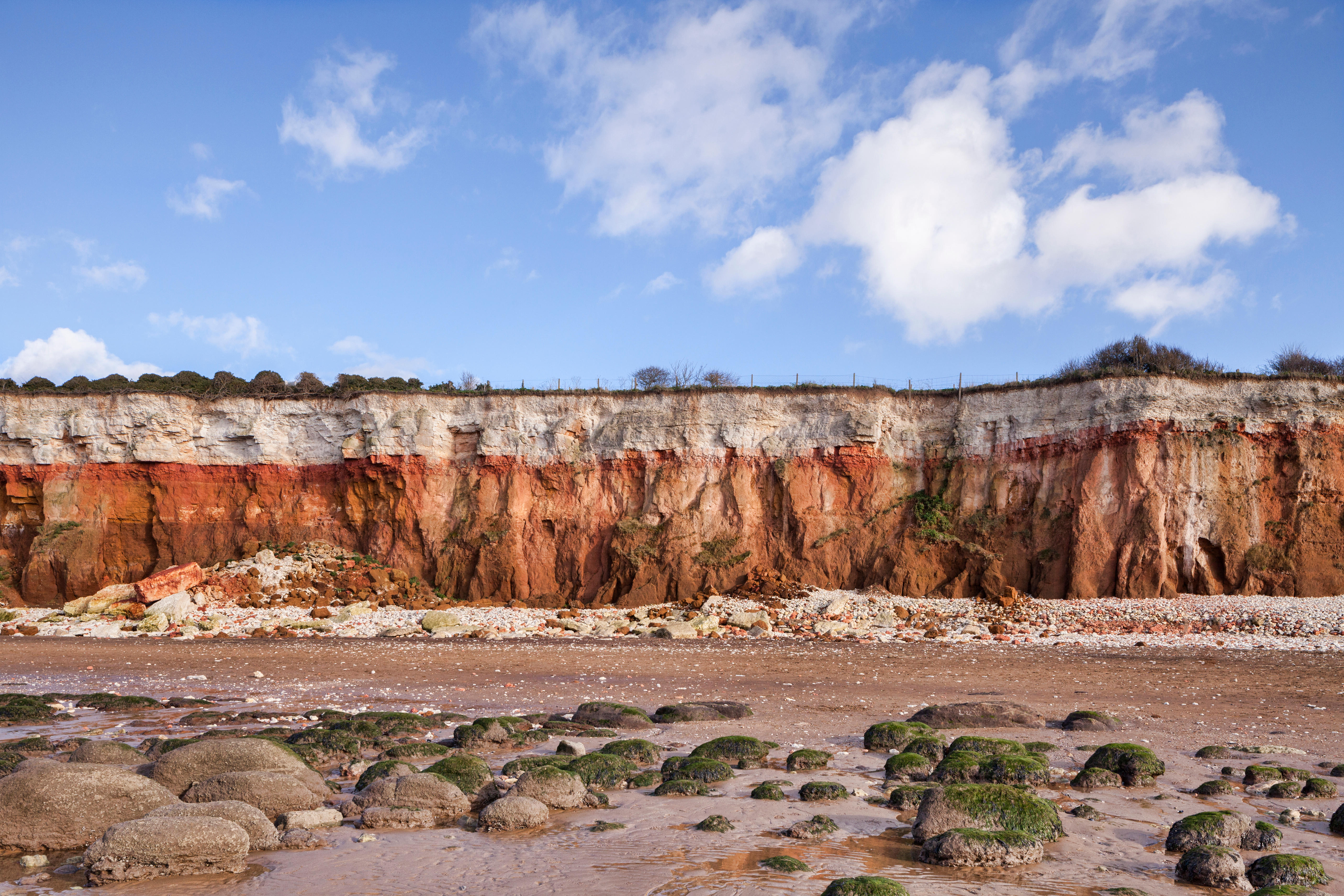 View of cliffs with white chalk overlaying red limestone in a colourful formation.
