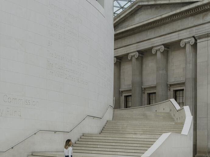 Frau, die eine breite Treppe unter einem geometrischen Glasdach hinaufgeht