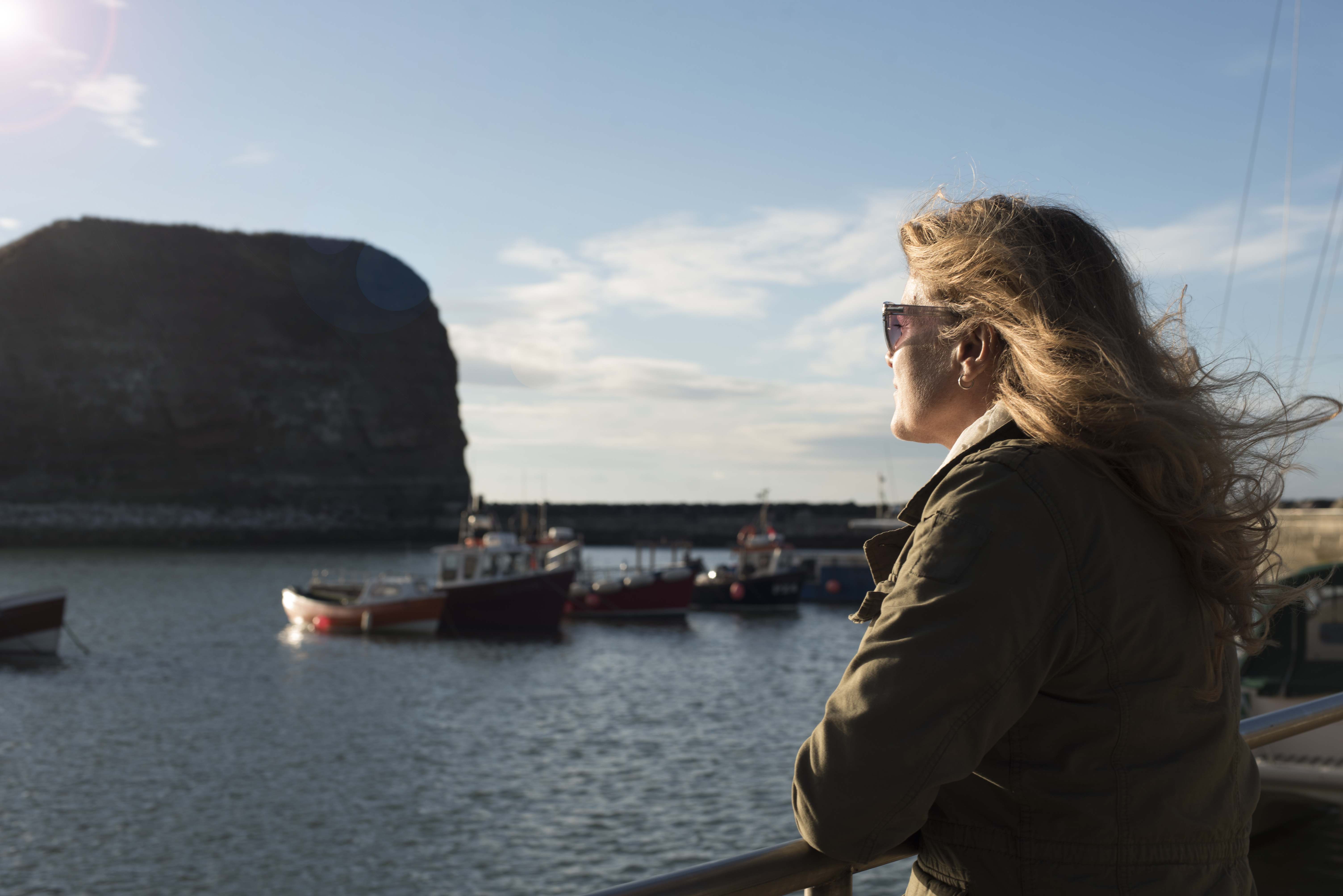 A woman, wearing sunglasses, looking out from the harbour
