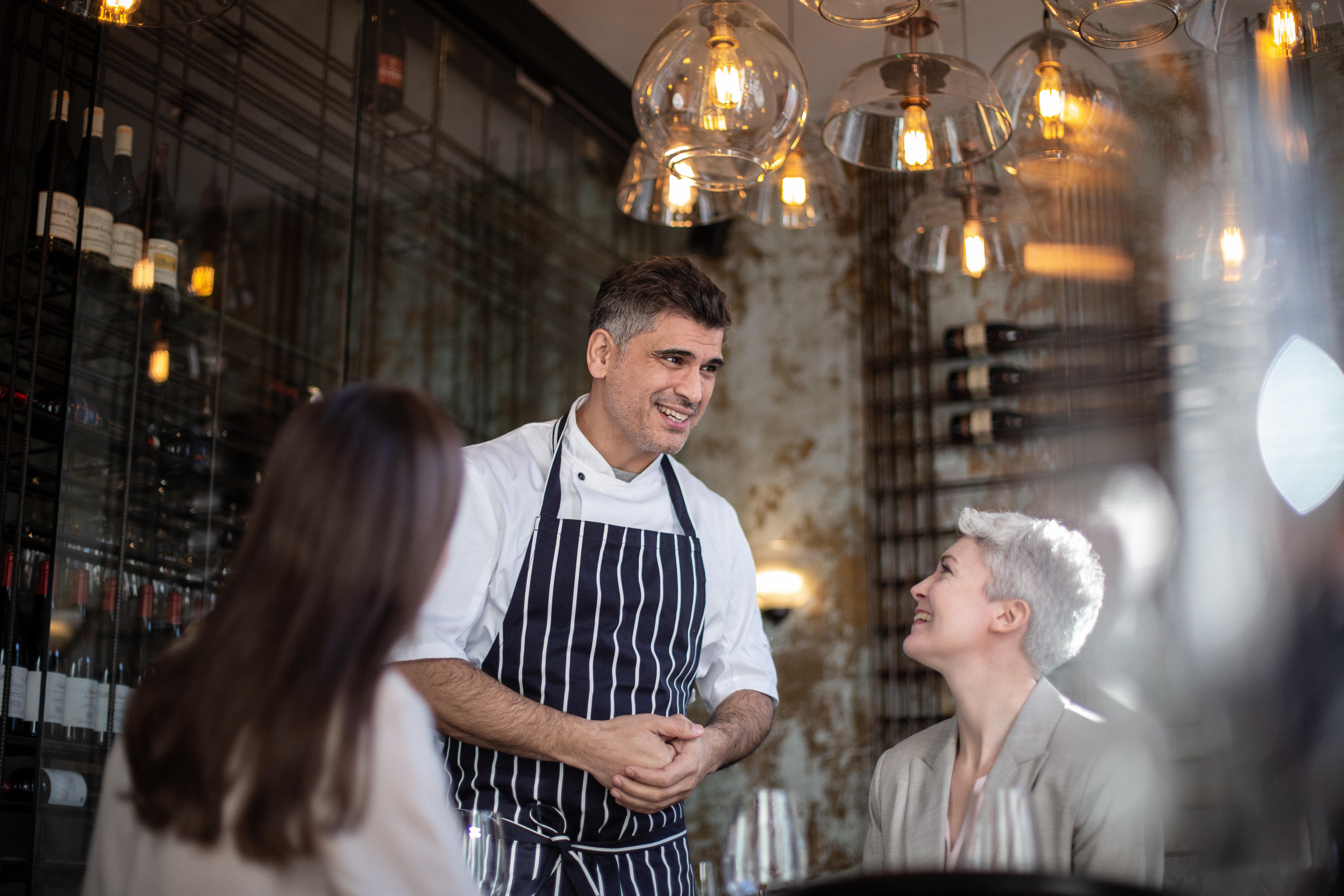 Un chef en uniforme saluant les clients dans son restaurant