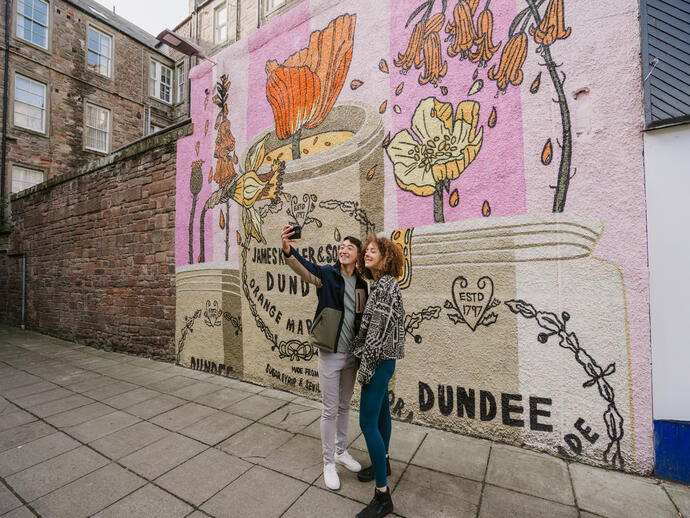 A man and a woman taking a selfie in front of the marmalade mural.